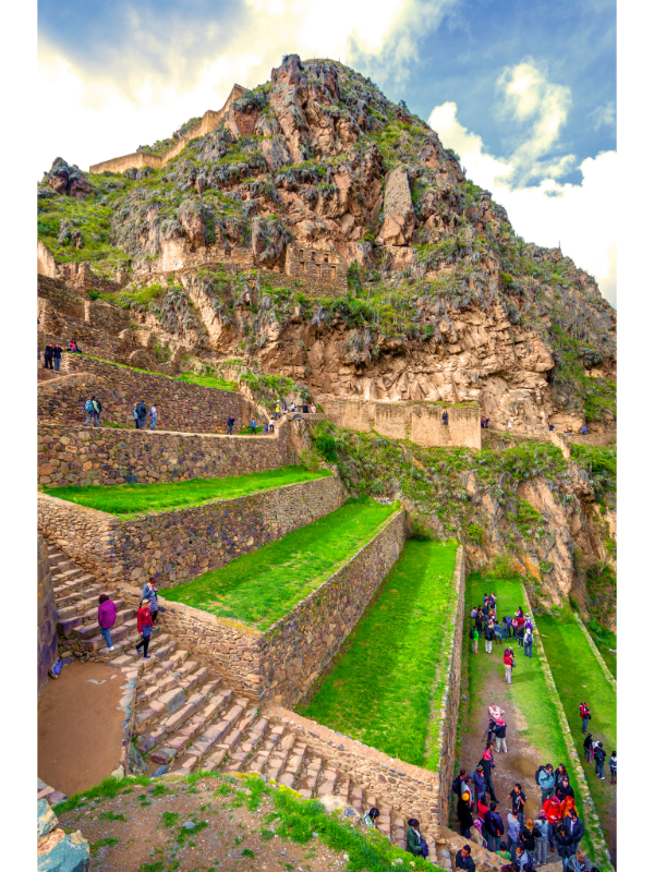 "Ancient Inca stone staircase at Ollantaytambo, Peru, with people climbing the steps and snow-capped mountains in the distance."